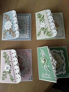 four cards with doily on them sitting on top of a wooden table next to each other