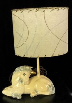 an animal lamp with a white shade on it's head and legs sitting next to a black background