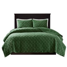 a bed with green bedspread and pillows on top of the headboard, in front of a white background