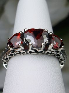 "Red Garnet Cubic Zirconia Ring Description Hearts Design#143 Made To Order This is a lovely Edwardian inspired ring in solid sterling silver. The gorgeous filigree ring is set with 3 heart cut simulated/Man-made garnet red CZ gemstones. The 2 smaller gems are 5mm in diameter, and the center one is 7mm in diameter. Notice the amazing etched band... The ring sits 1/4th\" (7mm) off the finger. The quality of the silver and gemstones are simply breathtaking... a ring that will last for countless ye Red Heart Cut Jewelry For Anniversary, Red Heart-cut Jewelry For Anniversary, Classic Heart-shaped Red Ruby Ring, Red Heart-shaped Ring With Prong Setting, Heart Shaped Red Ruby Ring For Wedding, Heart-shaped Red Ruby Wedding Ring, Heart-shaped Ruby Jewelry For Wedding, Classic Red Heart-shaped Ruby Ring, Heart-shaped Ruby Wedding Jewelry