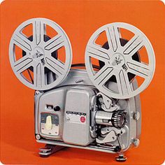 an old movie projector sitting on top of a orange background with the film reel attached to it