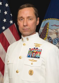 a man in uniform standing next to two flags