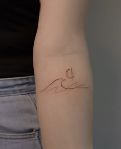 a woman's arm with a small wave tattoo on it