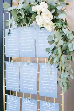 a wedding seating chart with flowers and greenery hanging from the side of a door