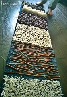 a child standing on top of a wooden floor next to an assortment of vegetables and nuts