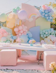 a table set up with balloons and pastel colors