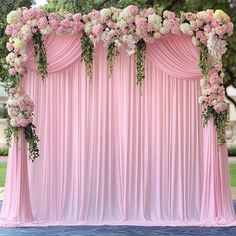 an outdoor wedding ceremony with pink draping and flowers on the back drop cloth