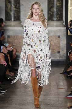 a model walks down the runway in a fringed dress