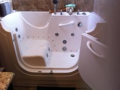 a bathroom with a walk in tub next to a sink and shower head mounted on the wall