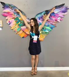 a woman standing in front of a wall with wings on it