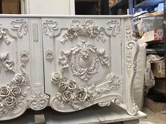 an ornate white cabinet with roses and scrolls painted on it's sides in a shop