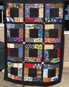 a large black quilt with many different colored squares on it's back and sides