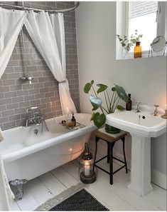 a white bath tub sitting under a window next to a sink and a candle holder