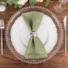 the place setting is set with silverware and green napkins, as well as flowers