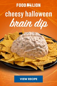 a black plate topped with chips and a cheesey halloween brain dip on top of it