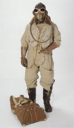 a man in an air force uniform standing next to a luggage bag and wearing goggles