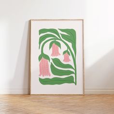 an art print with pink flowers on green leaves in front of a white wall and wooden floor