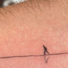 a person walking across a tight line with a small tattoo on their back side shoulder