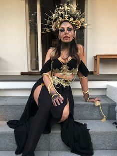 a woman sitting on the steps wearing a costume with chains and beads around her neck