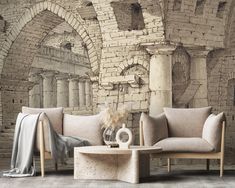 two couches and a coffee table in front of a brick wall with roman ruins on it