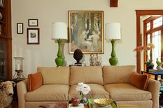 a living room with couches, lamps and pictures on the wall in it's center