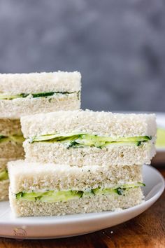 three sandwiches stacked on top of each other on a white plate next to a cup