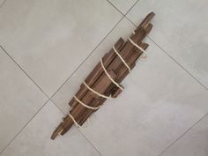 a piece of wood tied up with rope sitting on the floor next to a wall