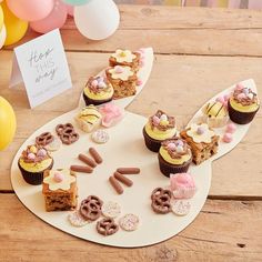 cupcakes are arranged on a plate near balloons