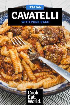 a plate full of pasta with meat and sauce on it, next to a knife and fork