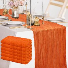 the table is set with orange napkins and place settings