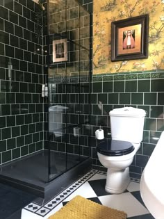 a black and white tiled bathroom with a walk in shower next to a toilet seat