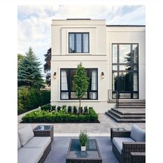 an outdoor living area with couches, tables and chairs in front of a white house