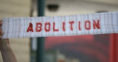 a person holding up a piece of paper with the word abolition written on it