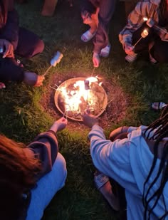 several people sitting around a fire pit on the grass