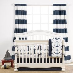 a white crib in front of a window with blue and white striped drapes