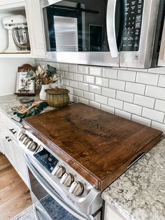 a wooden cutting board sitting on top of a kitchen counter next to an oven and microwave