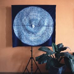 a blue painting on a wall next to a potted plant and a tripod light