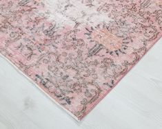 an area rug with pink and blue flowers on the top, in front of a white wooden floor