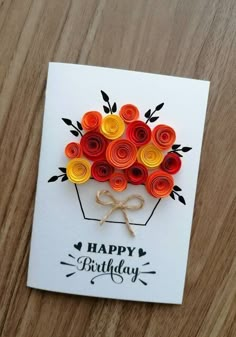 a birthday card with rolled paper flowers in the shape of a vase on top of a wooden table