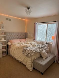 a bedroom with a bed, dresser and window in the corner that has lights on