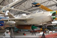 an airplane that is on display in a building with other planes and equipment around it