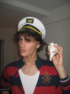 a young man in a sailor's hat holding a shell