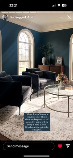 a living room with blue walls and white carpeted flooring, two black couches in the center