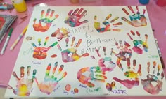 a birthday card with handprints on it sitting on a table next to paints and markers