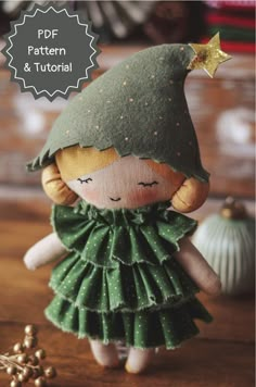 the doll is wearing a green dress and gold star on her head, while standing next to some ornaments