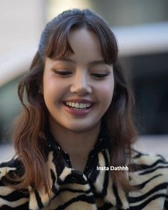 a young woman smiles as she looks down at her cell phone while wearing a black and white striped shirt