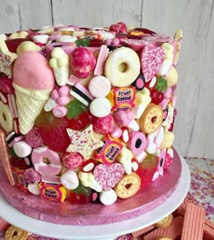 a pink cake covered in lots of different candies and donuts on top of it