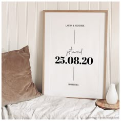 a white framed poster with the date and wedding date printed on it next to a pillow