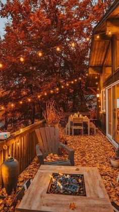 an outdoor fire pit surrounded by leaves and string lights on a deck in the fall