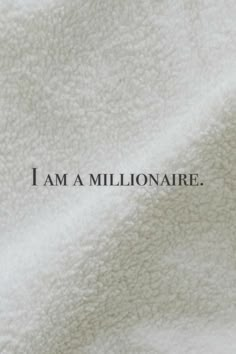 the words i am a millionaire are written in black ink on a white blanket